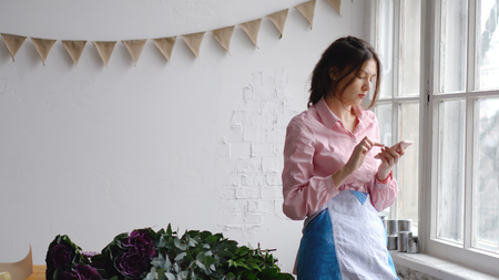 Businesswoman makes online sale of flowers using her phoneの写真素材