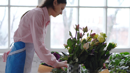 Florist at work: young woman making modern bouquet of different flowersの写真素材
