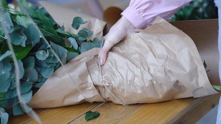 Florist ties a bouquet of large flowers from craft paperの写真素材