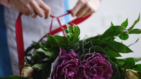 Professional florist artist swathes with a ribbon bouquet in the backgroundの写真素材