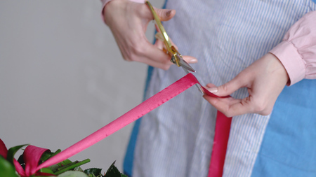Professional florist cutting ribbon of wedding bouquet at workshop, flower shop. Close up shotの写真素材