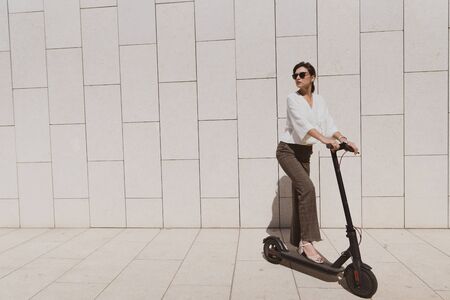 A woman uses an electric scooter in a park. The new gadget for fast movement around the city without...