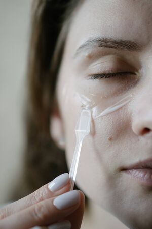 Close-up portrait of a woman - natural skin care using moisturizer. Stroking a face with a brush for applying makeup.の写真素材