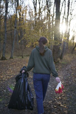 Pollution of nature and the environment. Woman with big black trash bag. The concept of artificial pollution of nature by peopleの写真素材