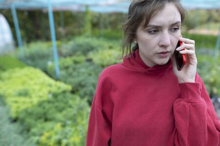 Female owner of a small eco-business. Service, talking with a client on the phone. Remote trade in eco products, young seedlings of evergreensの写真素材