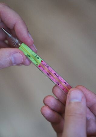 A medical thermometer in mens hands close-up. Covid-19 and the epidemic of infection