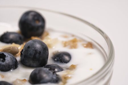 Blueberries in vegan yogurt in a transparent glass, healthy breakfast. Add the berry-shaped vitamins to the milk dessert. Close-upの写真素材