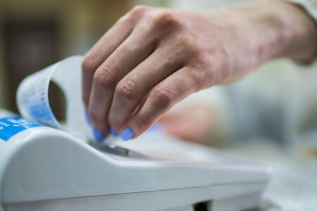 The seller rips off and checks the check close-up. White cash register close-upの写真素材