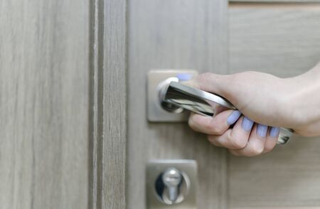 Young woman opens the door. Close-up female hand opens or closes the door.の写真素材