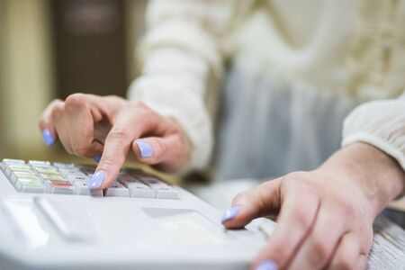 The cashier in the store comes to the checkout and knocks out the check. A salesman in a furniture office close-upの写真素材