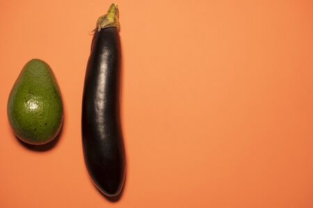 Fresh avocado and eggplant on a peach background. Healthy food, a place for textの写真素材