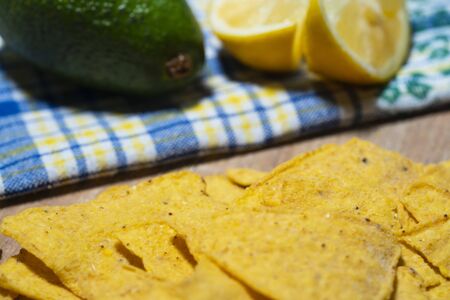 Nachos chips against a backdrop of lemon and avocado, close-up. Traditional Mexican snack