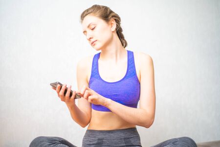 The woman turns on the music on the phone for meditation to relax and dive into Zen. Quarantine Yoga Class Onlineの写真素材