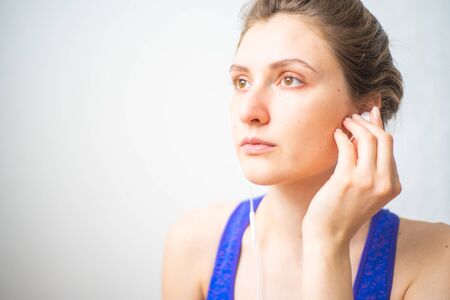 A woman inserts a headphone into her ear and turns on yoga meditation music. Relaxing music to clear the mind while performing asanasの写真素材