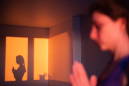 The shadow of the silhouette of a sports woman engaged in yoga. Asana pose for beginners, spiritual practice at sunsetの写真素材