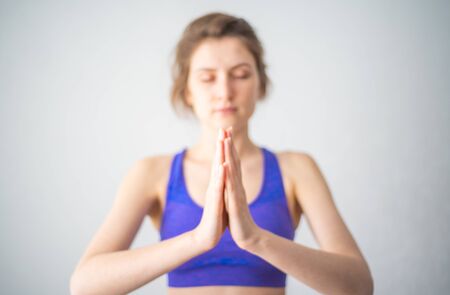 Yoga and meditation. Portrait of a beautiful woman in sportswear, hands folded, eyes closed