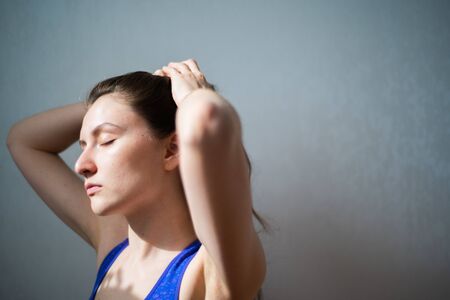 Female athlete collects hair in a braid for training. Preparing for sports closeup on a white backgroundの写真素材