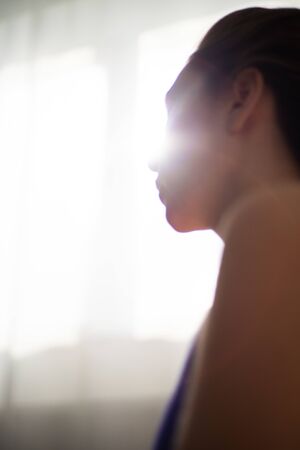 Breathing exercises on the background of the suns rays. Silhouette of a girl during yoga and meditationの写真素材