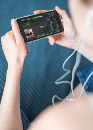 The girl watches a stream of online game on a smartphone in Twitch app. Live streaming on iPhone.