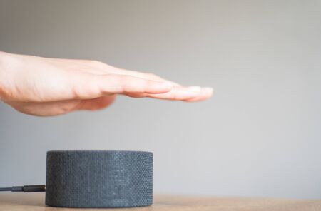 Regulating the volume of the portable speaker. A womans hand turns on and adjusts a smart device...