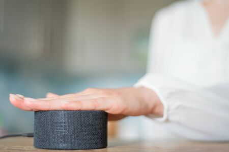 Young woman with her hand turns on the voice assistant in the kitchen copyspace. Smart home...