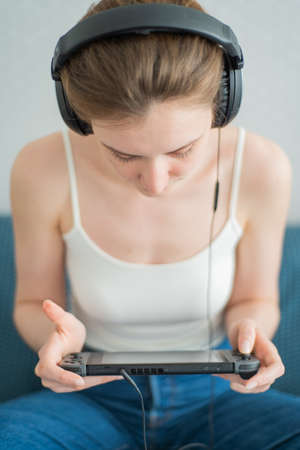 New York City, New York, USA - May, 15 2020, game console Nintendo Switch in the hands of a woman in Sennheiser headphonesのeditorial素材