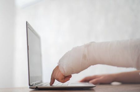 A person with a broken hand presses the button. Communication on the Internet with health restrictionsの写真素材
