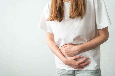 A woman holds on to her stomach during her period. Stomachache. Women's Health Cycle, Gynecology.