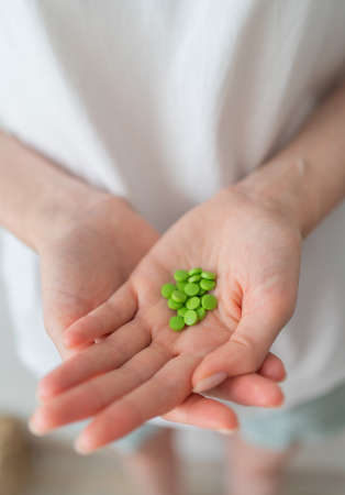 Oral contraceptives. Green pills in women's hands close up. Protection from unwanted pregnancies.の写真素材