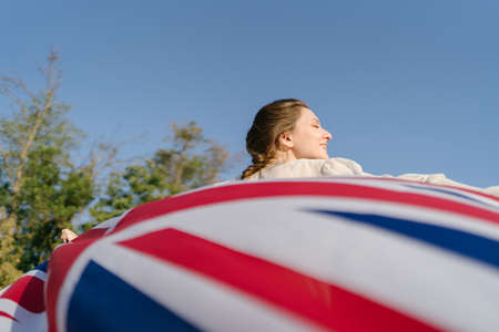 Britains flag beautifully develops in the hands behind a womanの写真素材