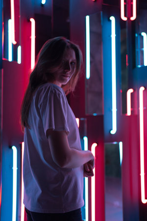 Beautiful silhouette of a young woman and looking at the camera in the rays of neon lightの写真素材