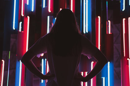 Silhouette of a mysterious woman on a neon background. Back view on a young woman in a fashion nightclubの写真素材
