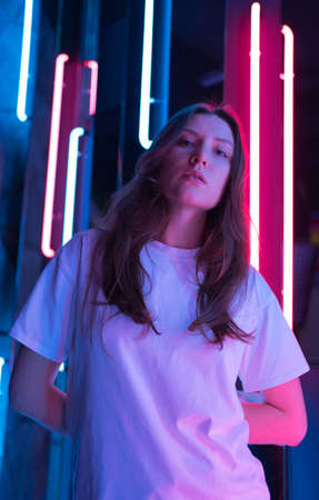 Lady in a beautiful light posing for the camera. Blue and pink lamps in the backgroundの写真素材