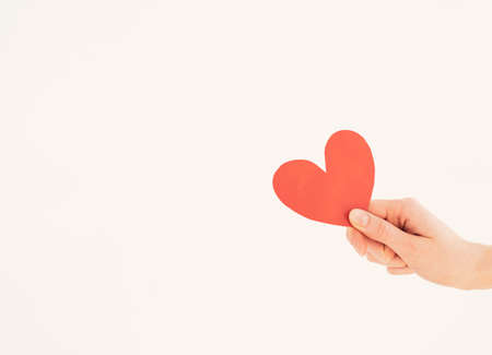 Red paper valentine in a womans hand on a white background. Valentines Dayの写真素材