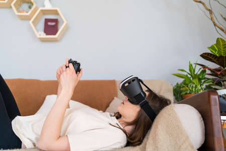Playing virtual reality lying on the couch. Modern Scandinavian interior. New experience
