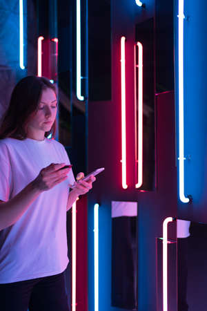 A woman holds a credit card and a phone in cyberspace. Online shopping and purchaseの写真素材