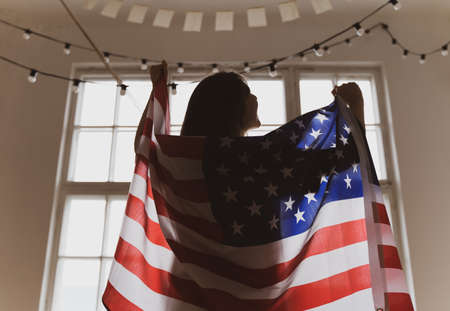 American winner. US flag. National celebration. Silhouette of a woman in the background of a windowの写真素材