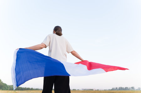 A woman walks with the flag of France at sunset. Patriotism and prideの写真素材
