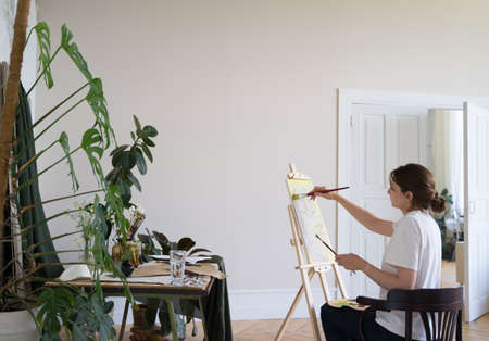 Entrepreneur artist. A young woman paints a picture in the studio. Professional creativityの写真素材