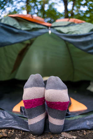 A woman in bright multi-colored socks lies in a tent in the woods. Campground. Relaxing in the wild aloneの写真素材