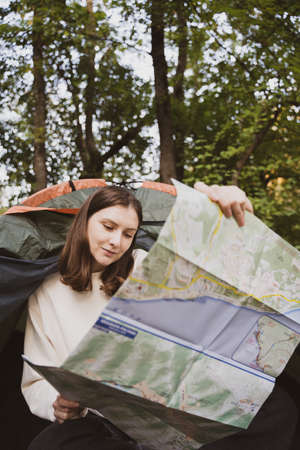 A female tourist exploring the map while sitting in a tent. Opens a new direction. Travel routeの写真素材