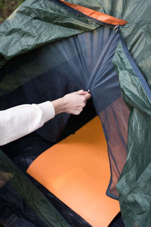 Close-up, the woman opens the lightning of the tent. Kemp. Travel, rest in the forestの写真素材