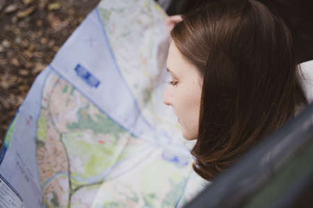 A woman traveler studies the map while lying in a tent. Opens a new direction for the hike. Trekking touristの写真素材