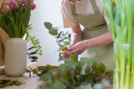 Service for creating festive bouquets. A young entrepreneur woman creates beautiful floristryの写真素材