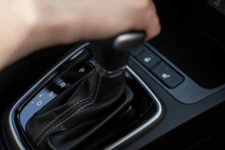 Person switches automatic transmission of automobile. Transportation management, close-up. Electronics and modern technologies in the carの写真素材