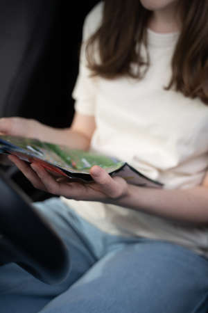 The driver in the car looks at the paper map, close-up. Holidays on a road tripの写真素材