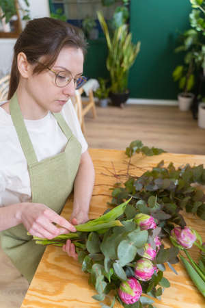A professional florist works in a flower shop. Create a color arrangement. The concept of spring and plantsの写真素材