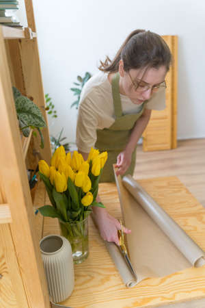 Gardeners office. Care of plants and flowers. Florists shop, woman seller creates a bouquetの写真素材