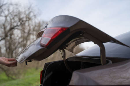 Person opens the trunk of the car, side view