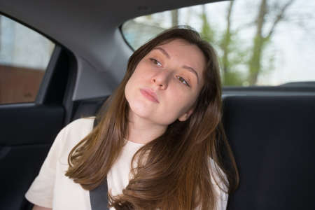 Beautiful young woman sits in a taxi and looks around. Passenger of the car, businesswomanの写真素材